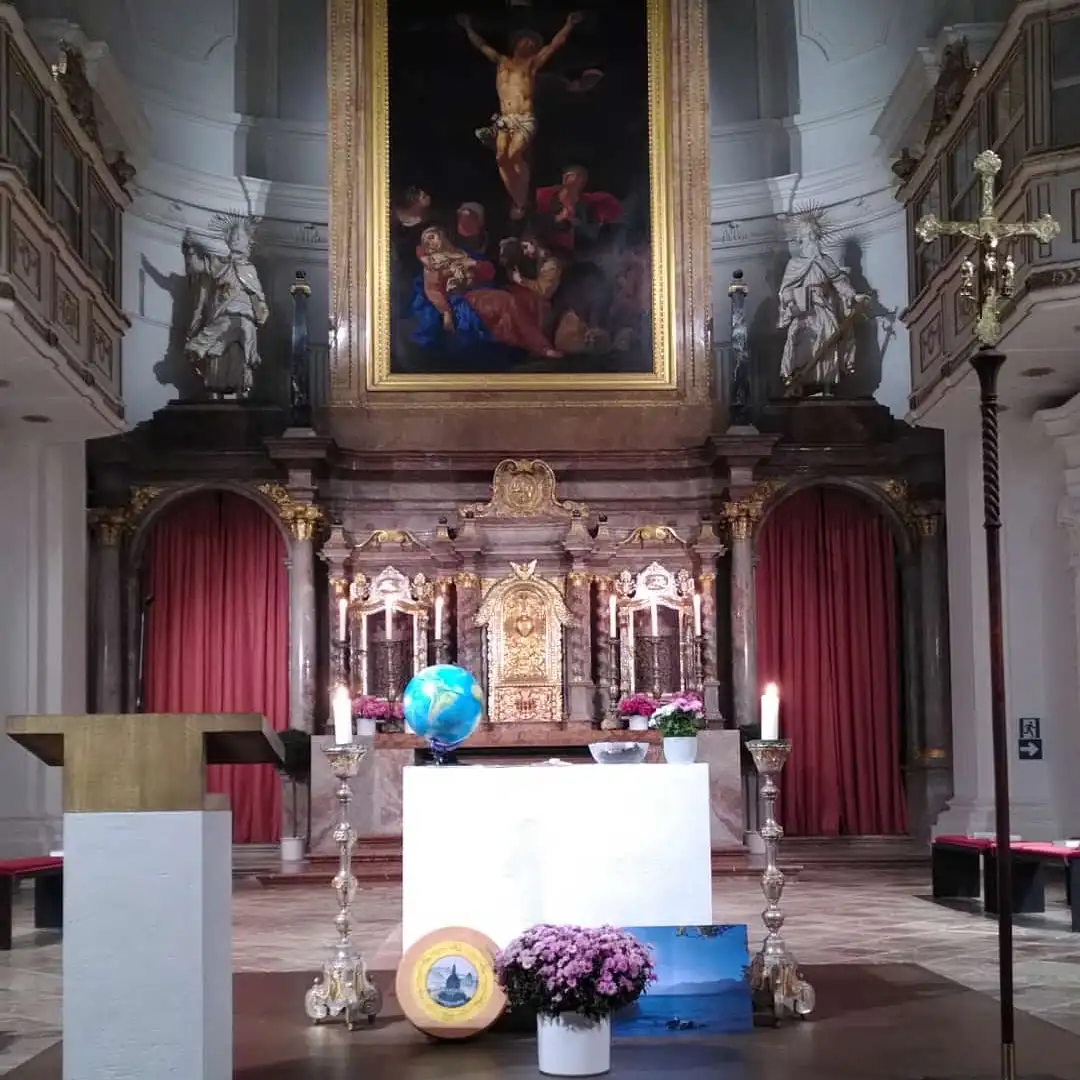 Das Bild zeigt einen geschmückten Altar in einer Kirche. Kerzen brennen. Vor dem Altas stehen Blumen.