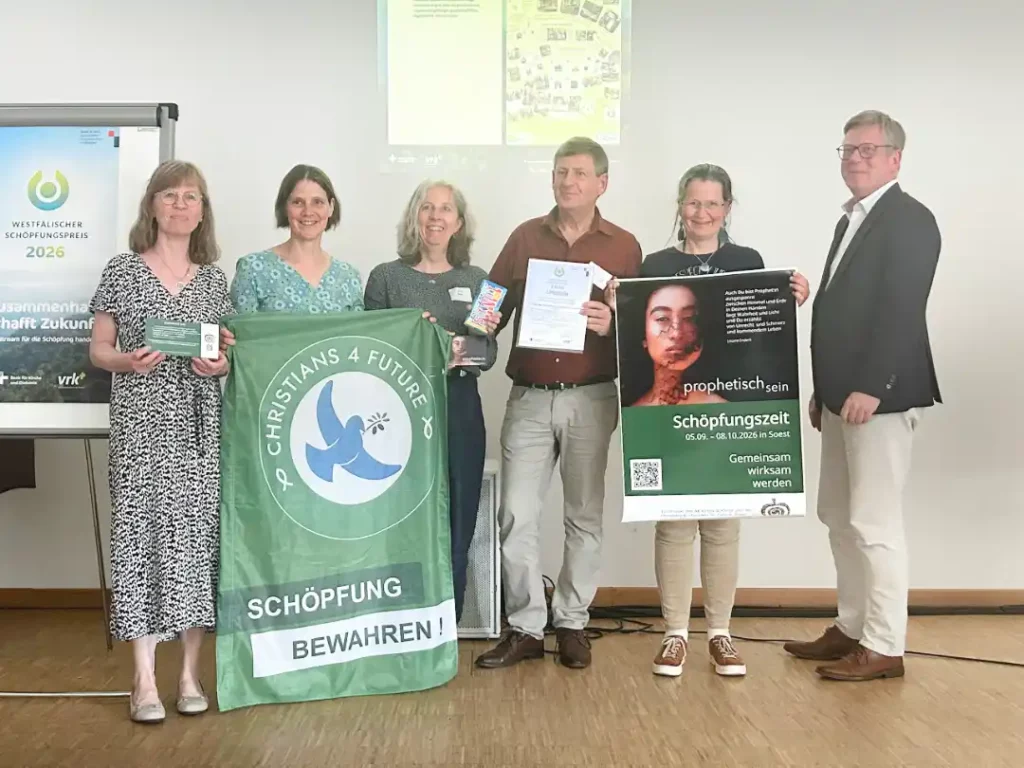 Das Bild zeigt eine Gruppe von sechs Menschen, die freundlich in die Kamera schauen und lächeln. Links im Bild die Fahne der Christians for Future. Zwei Menschen halten ein Plakat mit dem Titel "Schöpfungszeit".