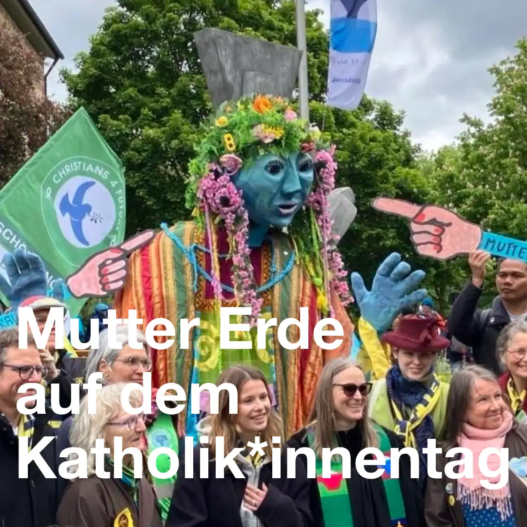 Das Bild zeigt eine Gruppe Menschen, die um eine große Figur herum stehen. Die Figur ist mit Blumen und Tüchern geschmückt und soll "Mutter Erde" darstellen. Auf dem Foto ist auch Luisa Neubauer zu sehen. Text: Mutter Erde auf dem Katholik*innentag.