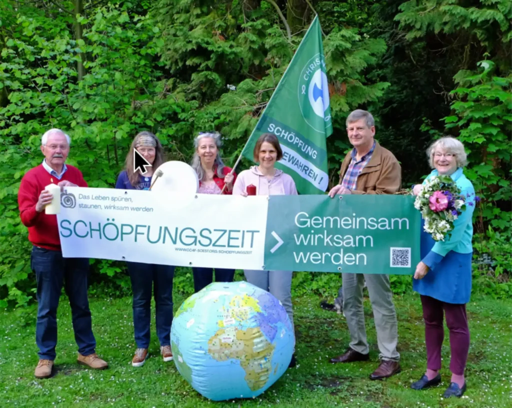 Das Bild zeigt sechs Menschen, die im freien Stehen und vor sich ein Transparent halten. Davor liegt eine aufblasbare Erdkugel und im Hintergrund ist das Banner der Christians for Future sichtbar. Text auf dem Banner: "Das Leben spüren, staunen, wirksam werden. Schöpfungszeit. Gemeinsam wirksam werden.".